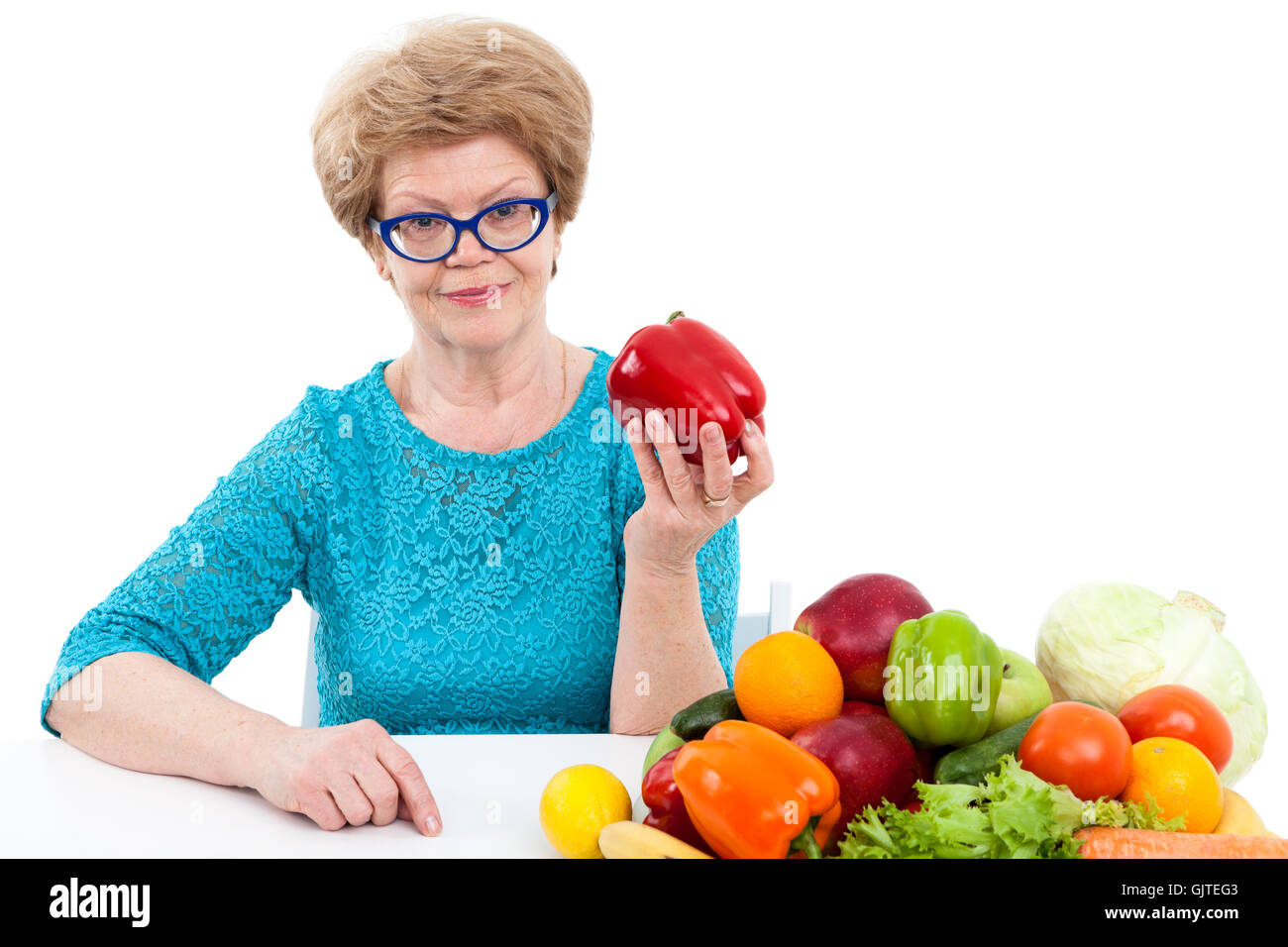 Aîné attrayant Caucasian woman showing poivron rouge, les légumes frais et les fruits sont sur la table, isolé sur blanc backgroun Banque D'Images