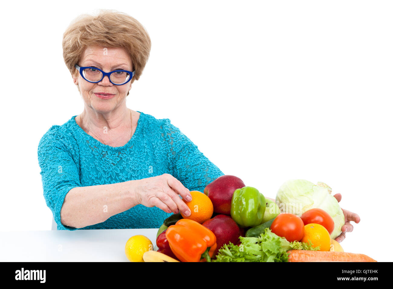 Smiling woman recueille les fruits et légumes frais sur la table, isolé sur fond blanc Banque D'Images