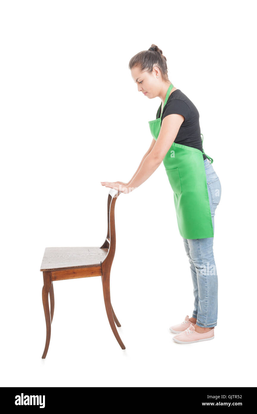 Vue latérale du jeune employé en uniforme de travail holding chaise en bois isolé sur fond blanc Banque D'Images