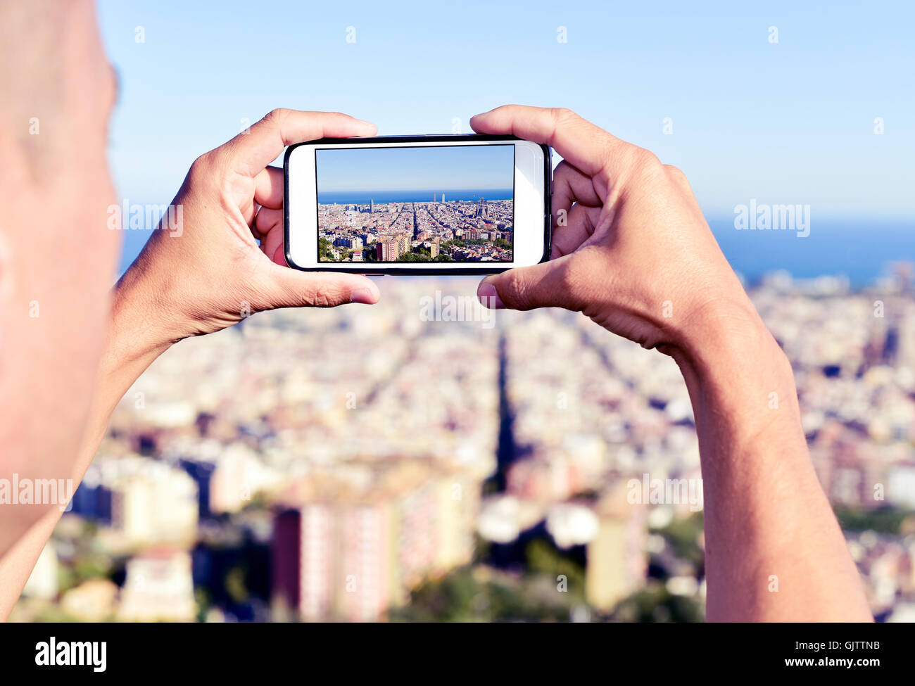 Libre d'un jeune homme de race blanche de prendre une photo de Barcelone, Espagne, du dessus avec son smartphone Banque D'Images