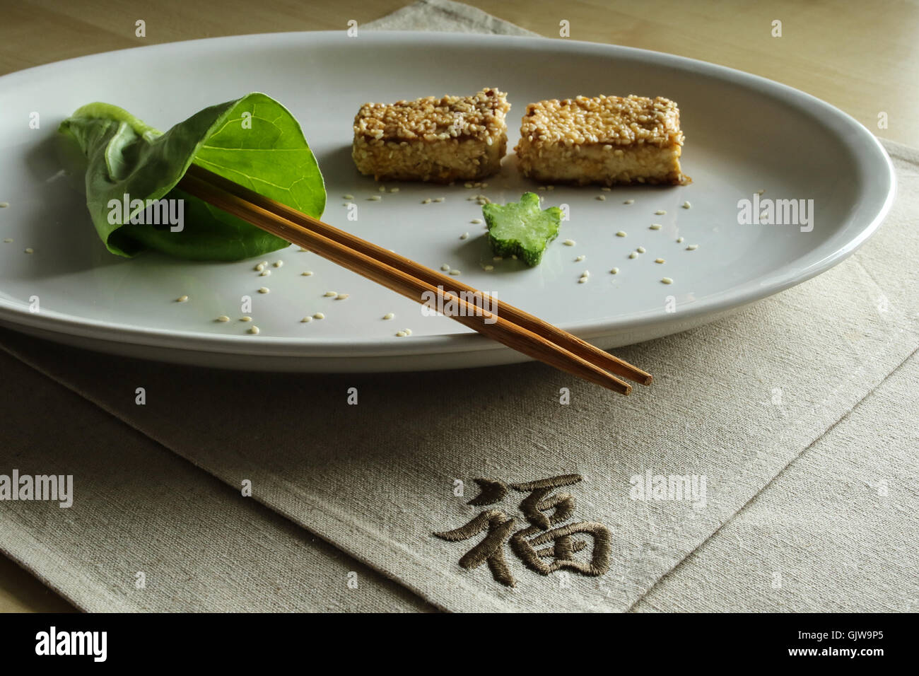 Signe Chinois Japonais le bonheur sur le dîner, deux ronds de tofu au sésame et baguettes Banque D'Images