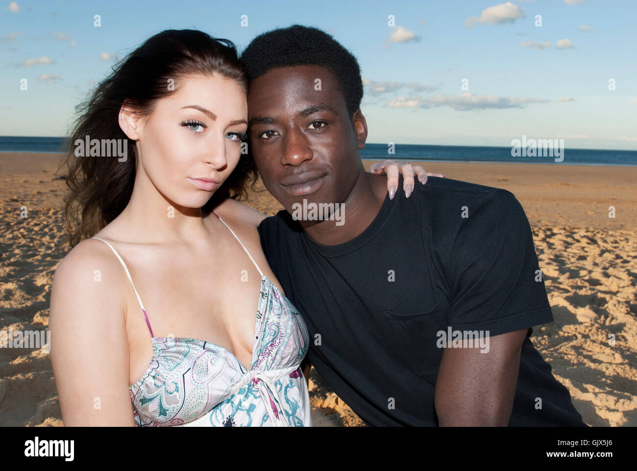 Beau couple mixte multiculturelle de la tête et des épaules la course ensemble à de graves sur la plage romantique Banque D'Images