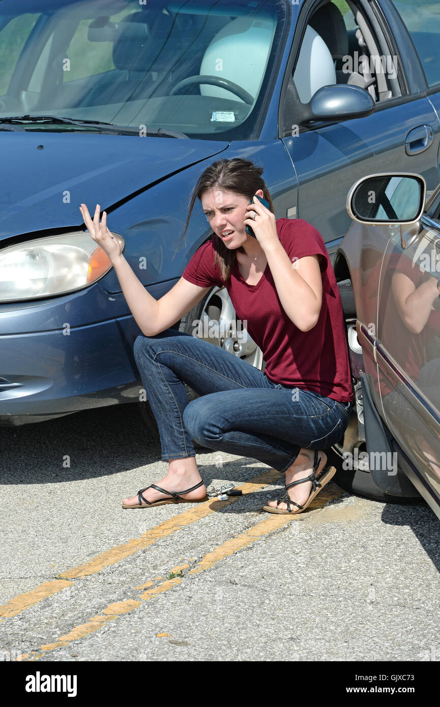 Young woman using cell phone après accident de voiture Banque D'Images