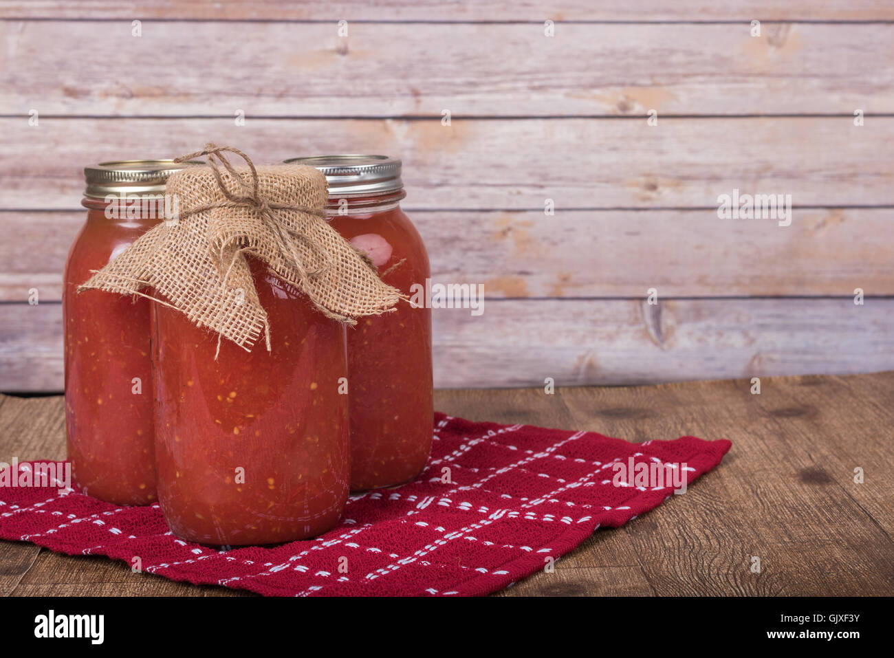 Trois pots de sauce tomate en conserve maison rustique en bois Banque D'Images