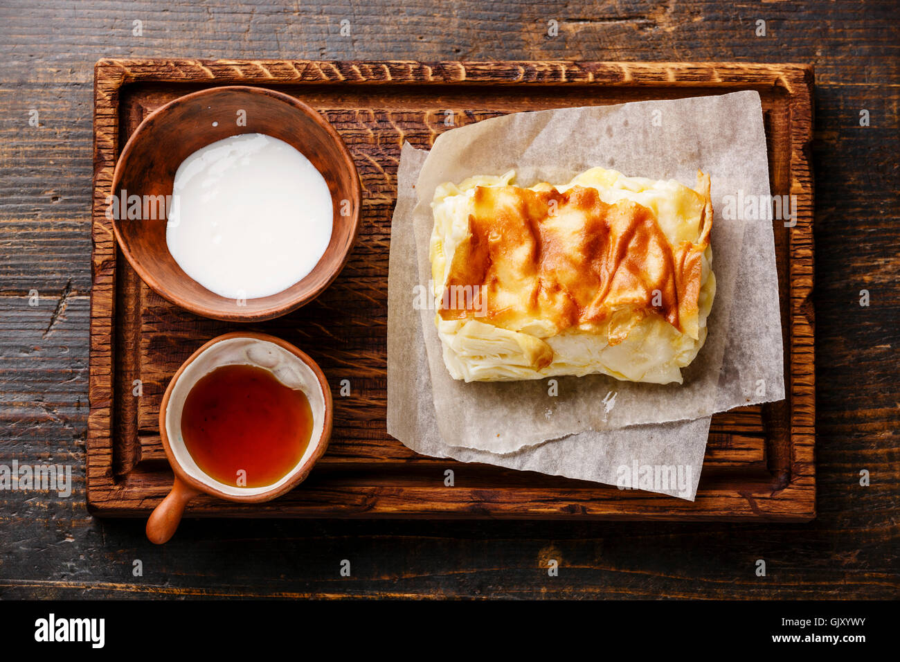 La couche de fromage géorgien traditionnel pie Achma avec sauce au yogourt crémeux matsoni et miel sur fond de bois Banque D'Images