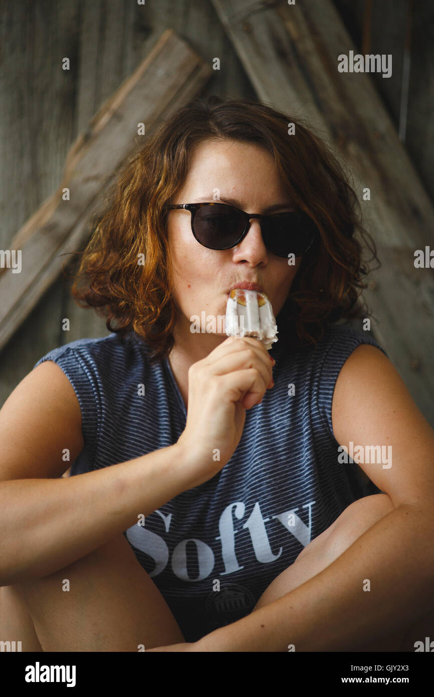 Popsiclesitting girl eating tannées en face de la porte en bois Banque D'Images