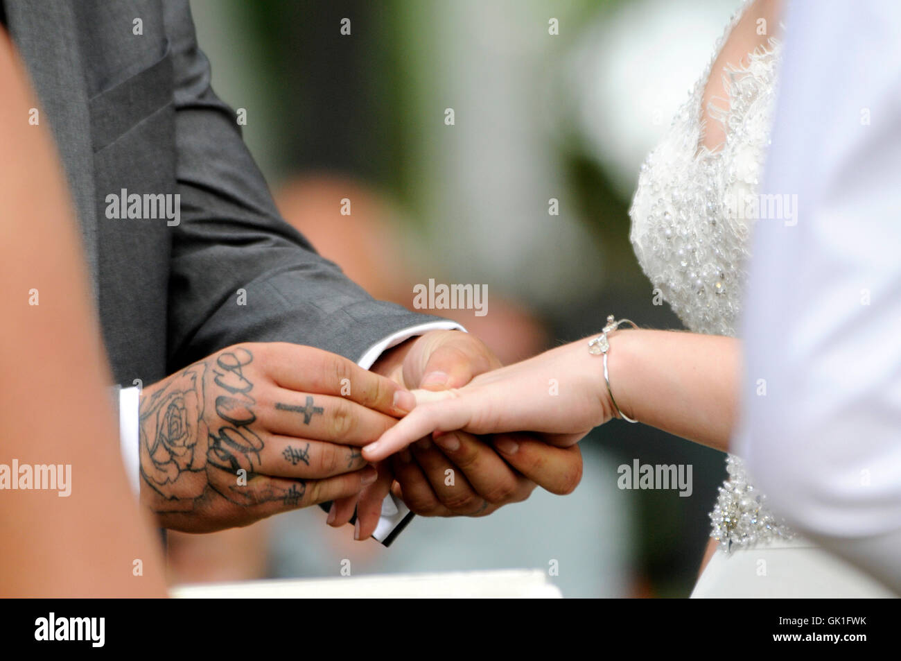 Groom plaçant anneau de mariage sur la main de son épouse. Mariage en plein air. Banque D'Images