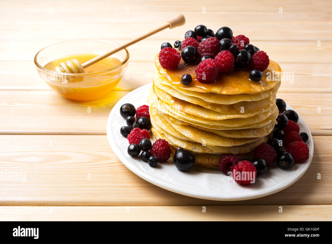 Crêpes maison avec du miel et de baies fraîches. Pile de crêpes Petit déjeuner servi avec bleuet, framboise et cassis. Banque D'Images