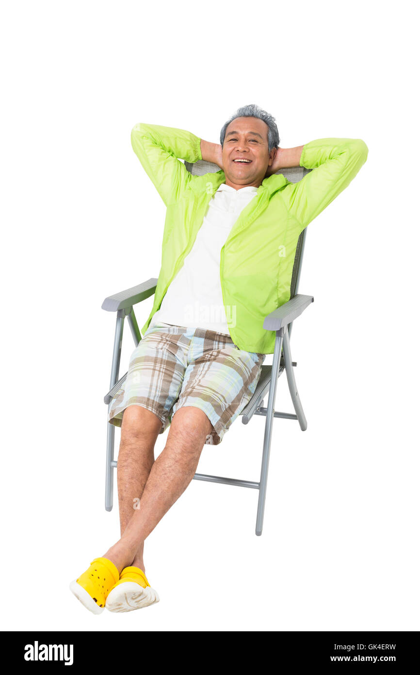 Un homme âgé assis sur une chaise de plage Banque D'Images