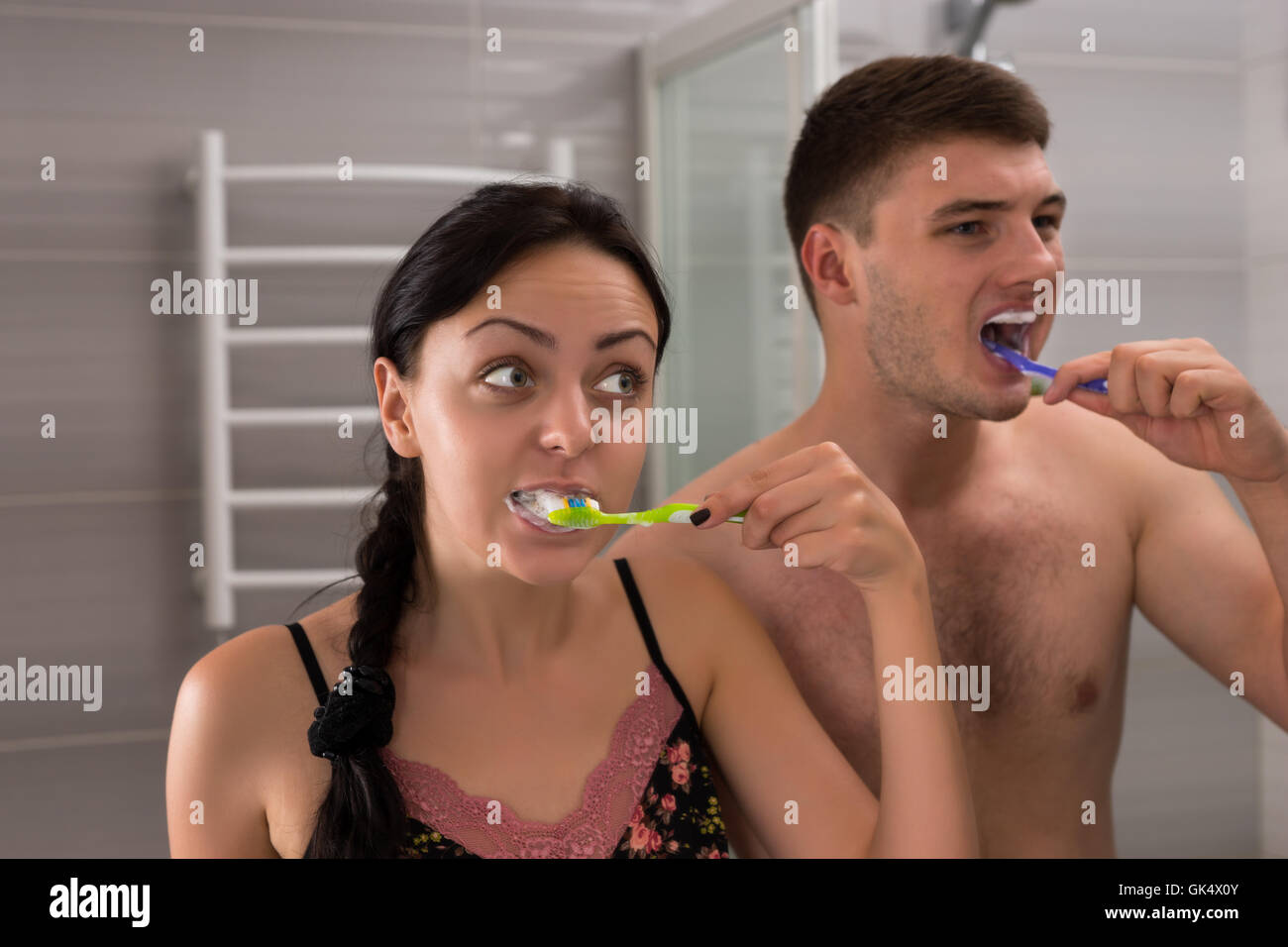 Close-up jeune paire se brosser les dents, debout devant un miroir dans la salle de bains moderne carrelée à la maison Banque D'Images