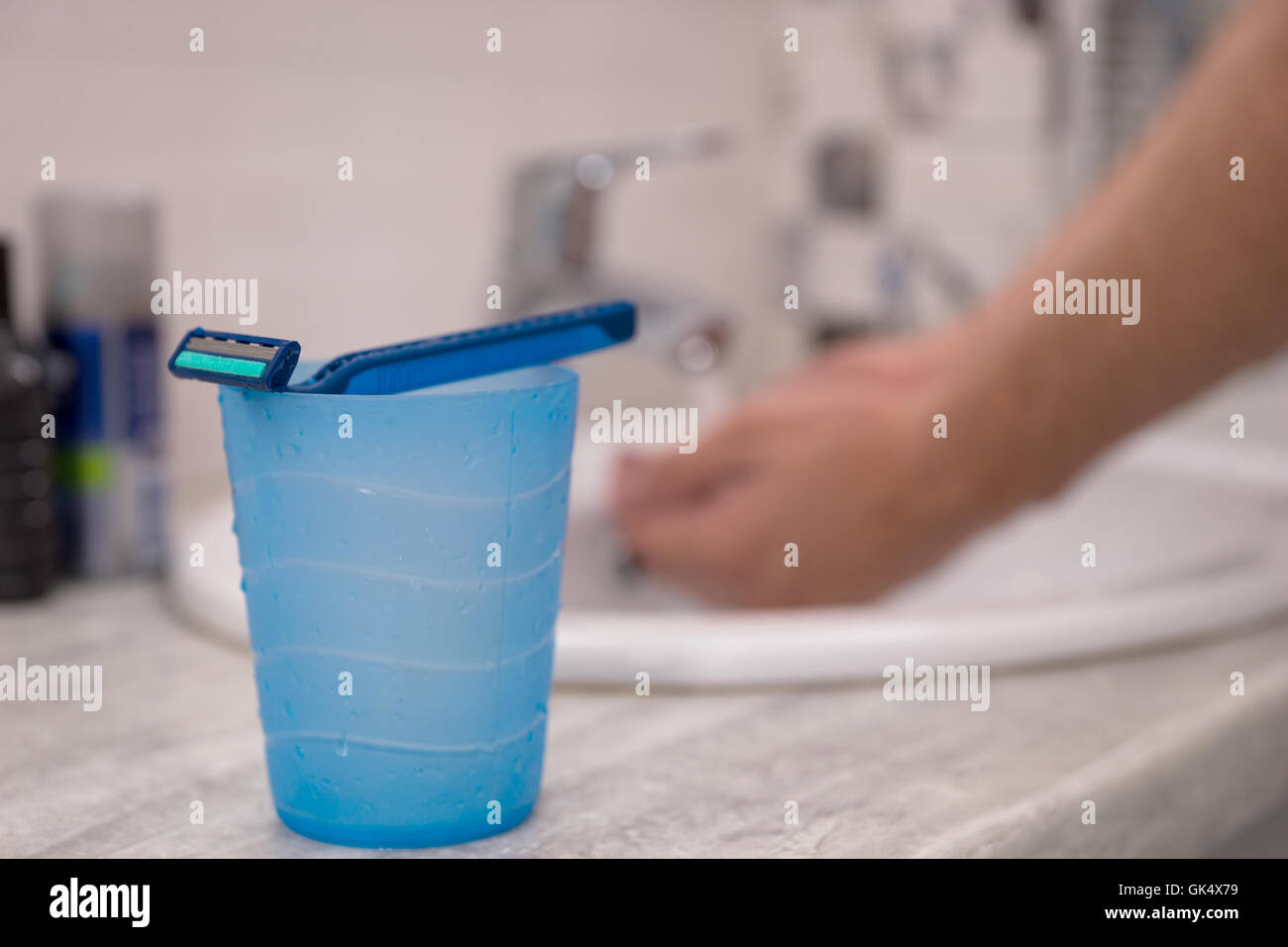La cuvette avec un homme et il sur razer lave son hahds dans vasque sur un arrière-plan dans la salle de bains moderne carrelée à la maison Banque D'Images