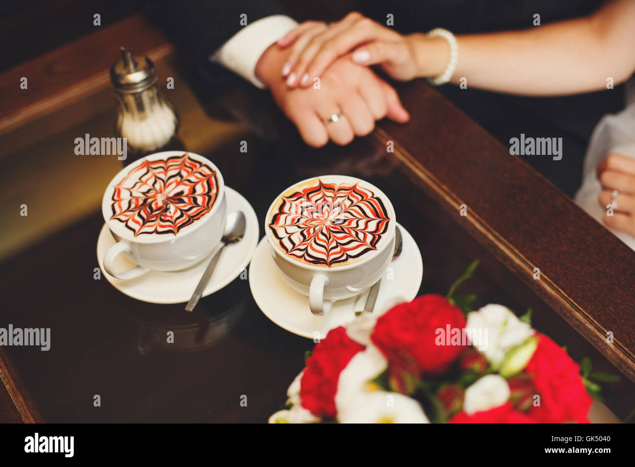 Mains de jeunes mariés sur la table, des tasses à café latte Banque D'Images
