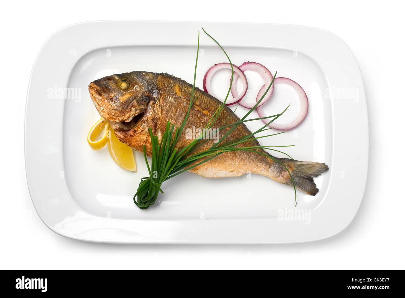 Le poisson grillé sur une plaque avec des oignons et du citron Banque D'Images