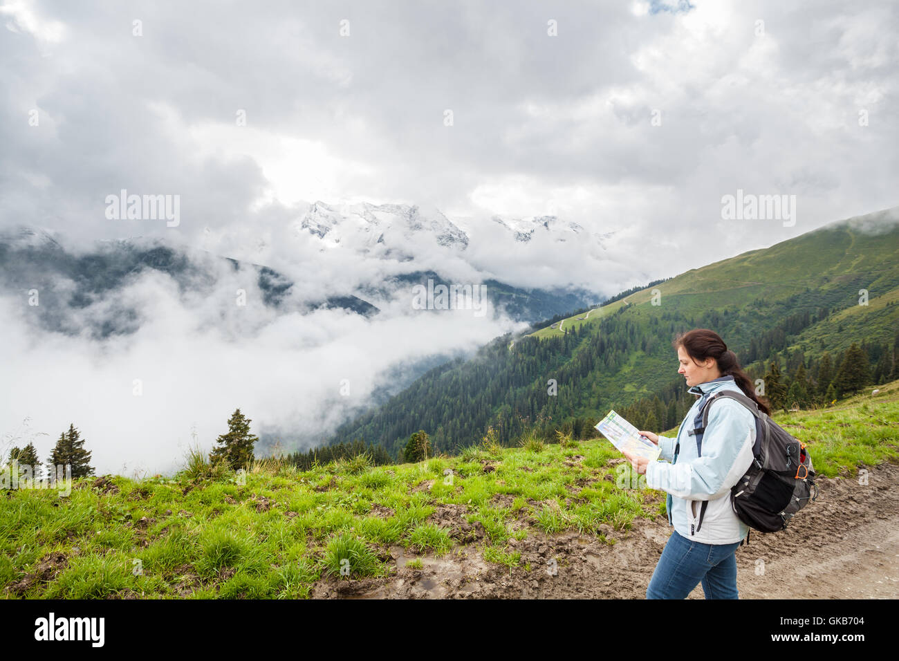 Sac à dos femme avec la lecture d'une carte sur un chemin de montagne Banque D'Images