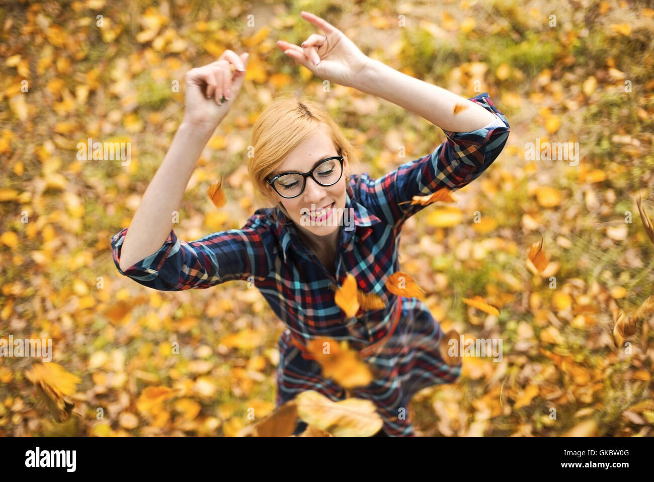 Jeune fille danser sous les feuilles qui tombent en automne park Banque D'Images