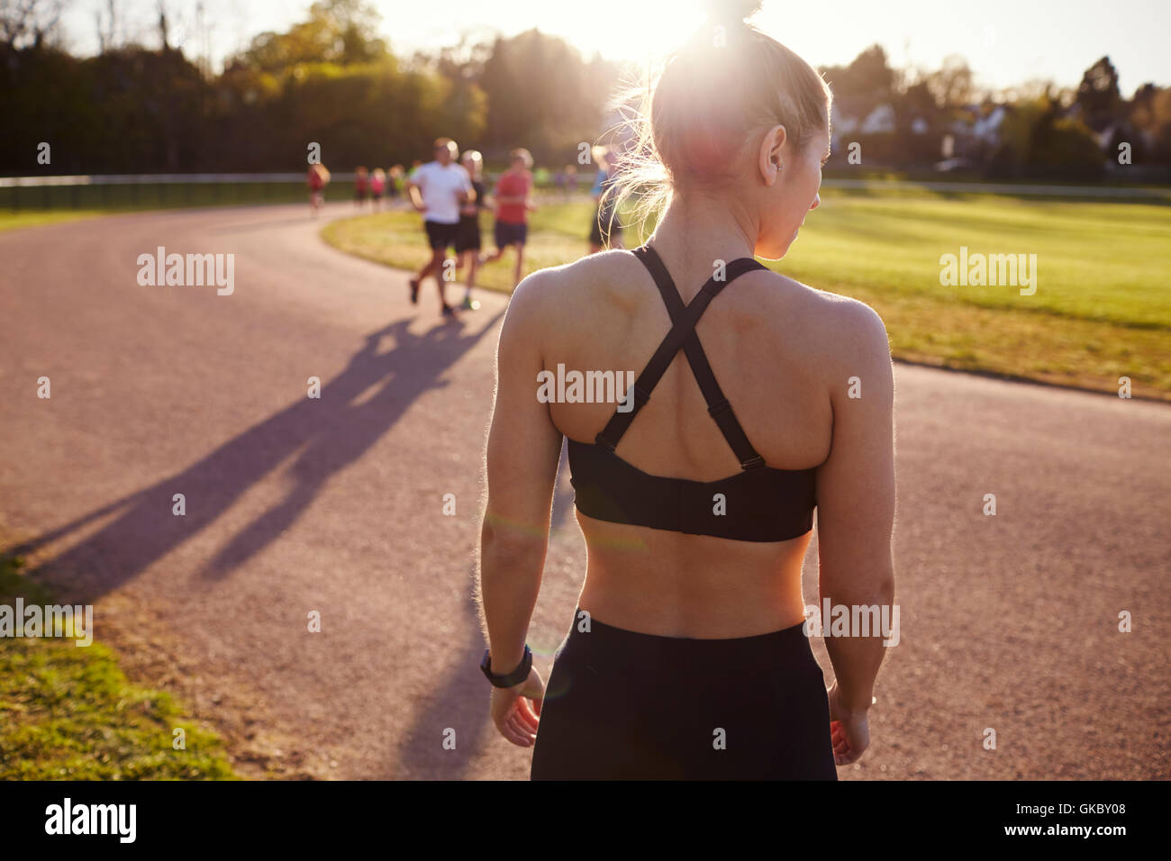 Vue arrière de femme debout par piste de jogging extérieure Banque D'Images