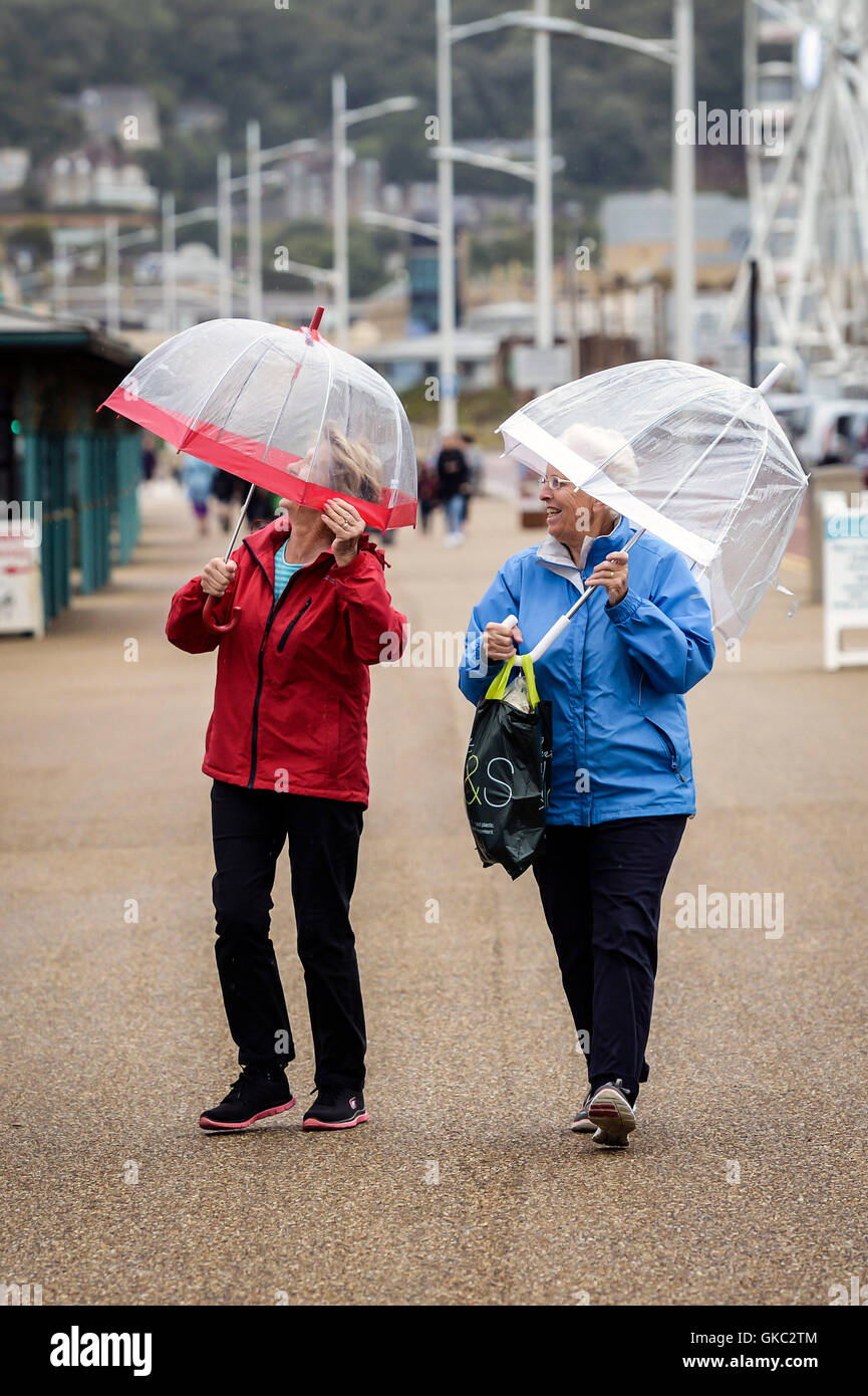 Deux dames avec parasols à pied le long de la promenade du front de mer à Weston-super-Mare, où un changement de température s'est imposé dans la ville balnéaire de Somerset et Nath19 Remplacer le soleil chaud des conditions de ces derniers jours. Banque D'Images
