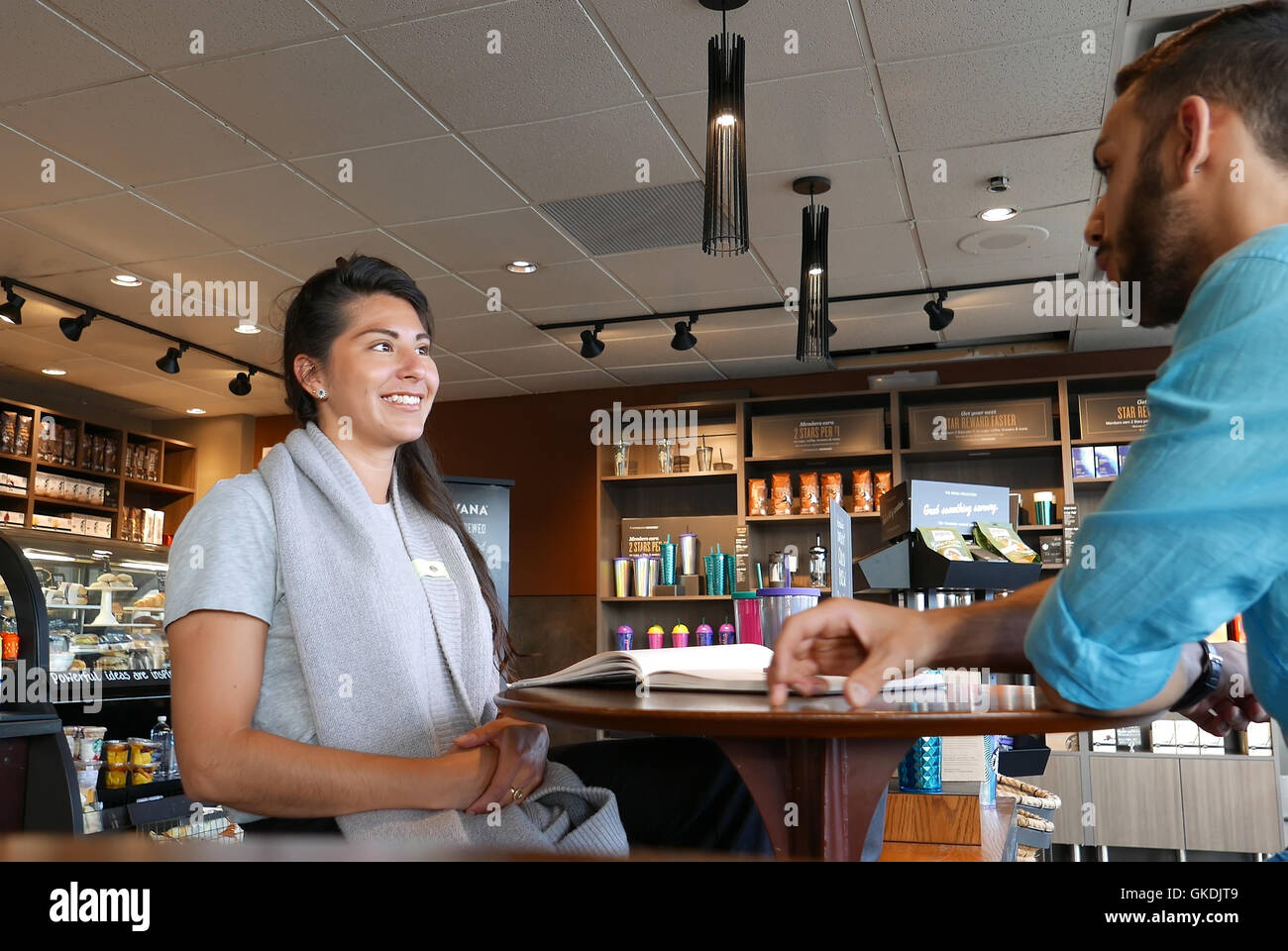 Un côté de gens de boire du café et discuter affaires à l'intérieur magasin Starbucks Banque D'Images