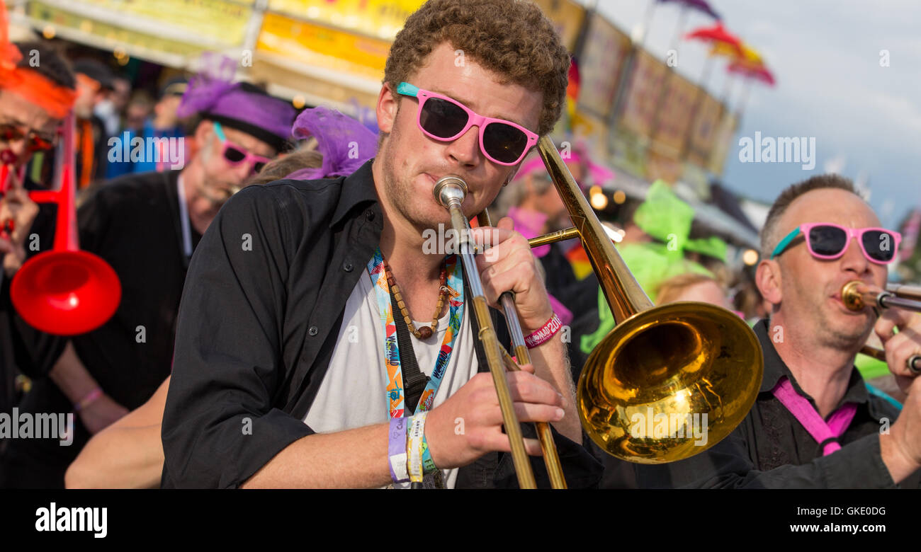 Un homme portant des lunettes de lecture trombone interprètes dans un défilé de musique au festival WOMAD, Wiltshire, Royaume-Uni Banque D'Images