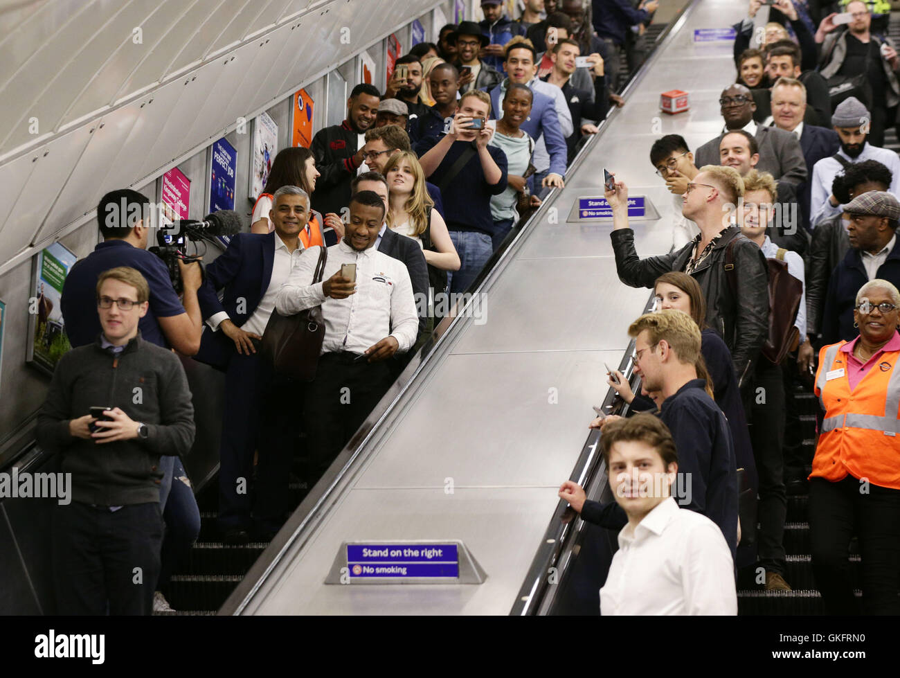 Les membres du public de prendre des photos de maire de Londres Sadiq Khan (à gauche) comme il se déplace vers le bas un escalier mécanique à la station de métro de Brixton, lors du lancement de la nuit de Londres, le Tube que les trains fonctionnent toute la nuit le vendredi et le samedi sur la ligne Victoria et certaines parties de la ligne centrale, avec le Jubilé, Northern et Piccadilly lignes suivantes à l'automne. Banque D'Images