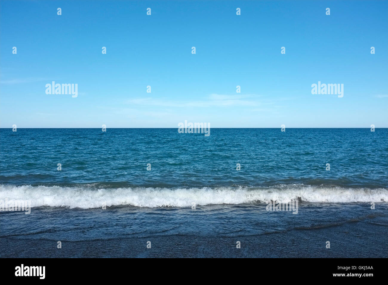 Photographie de fond marin avec ciel bleu et sable foncé Banque D'Images