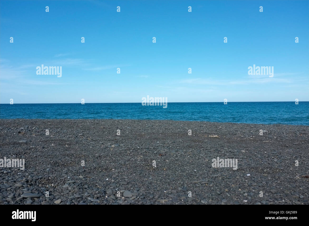 Photographie de fond marin avec ciel bleu et sable foncé Banque D'Images