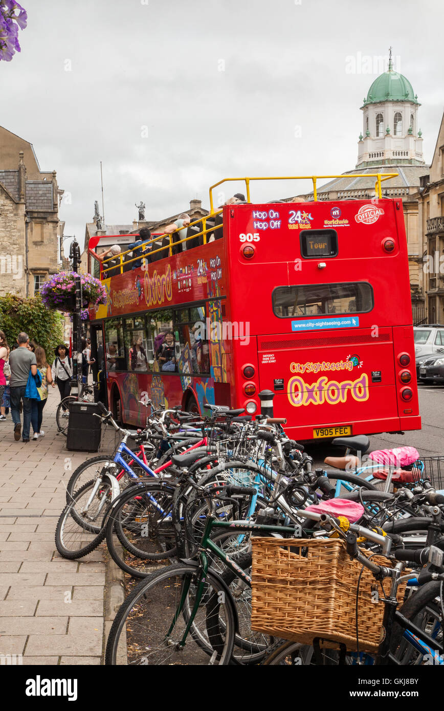 Open top bus à impériale, visite de Oxford, avec de nombreux cycles garée derrière elle Banque D'Images