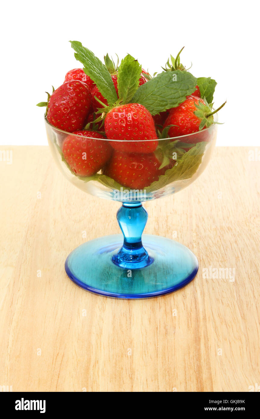Fraises fraîches et de feuilles de menthe dans un verre sundae sur une table en bois sur un fond blanc. Banque D'Images
