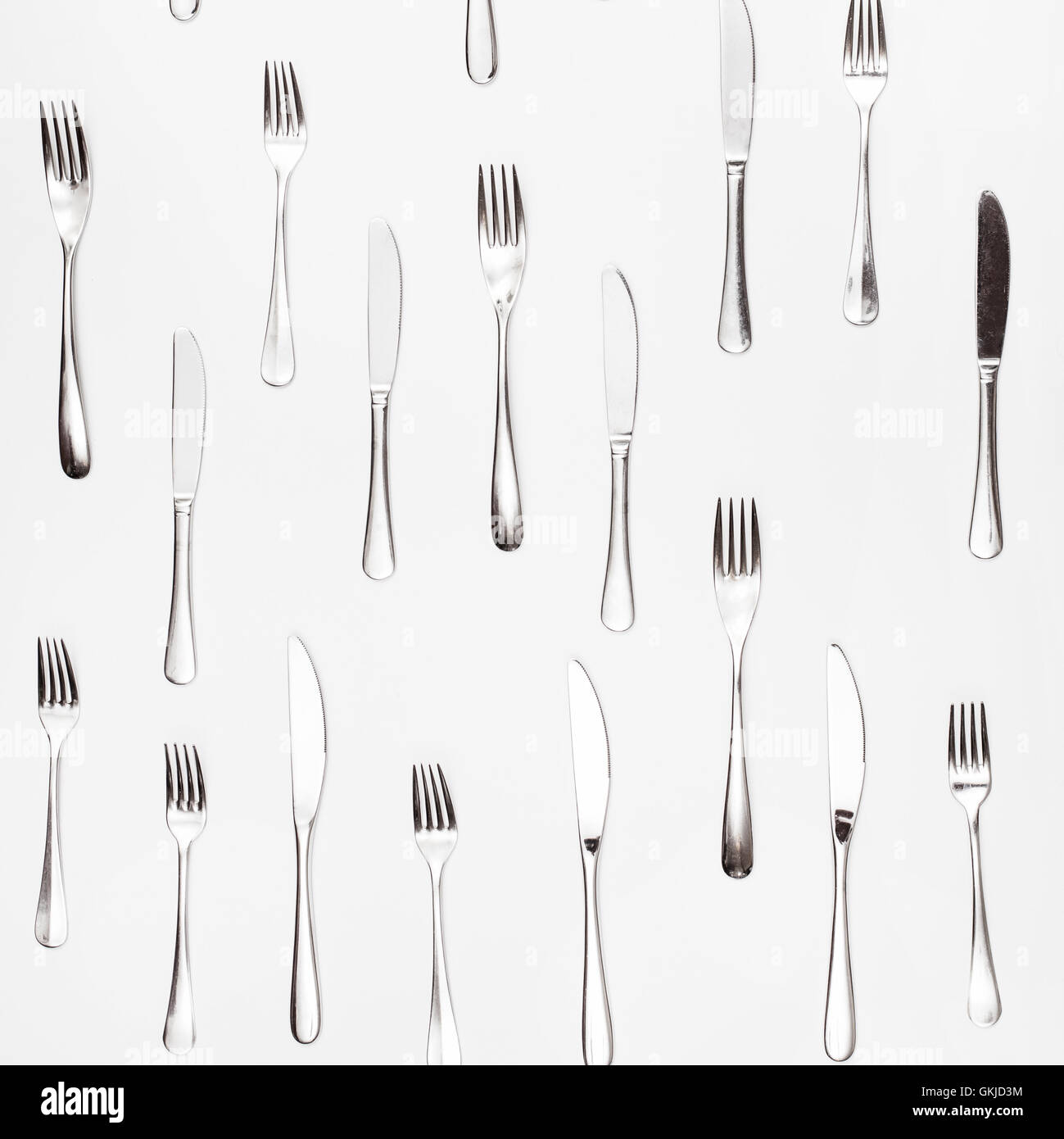 Couteaux et fourchettes de table organisées sur fond carré blanc Banque D'Images
