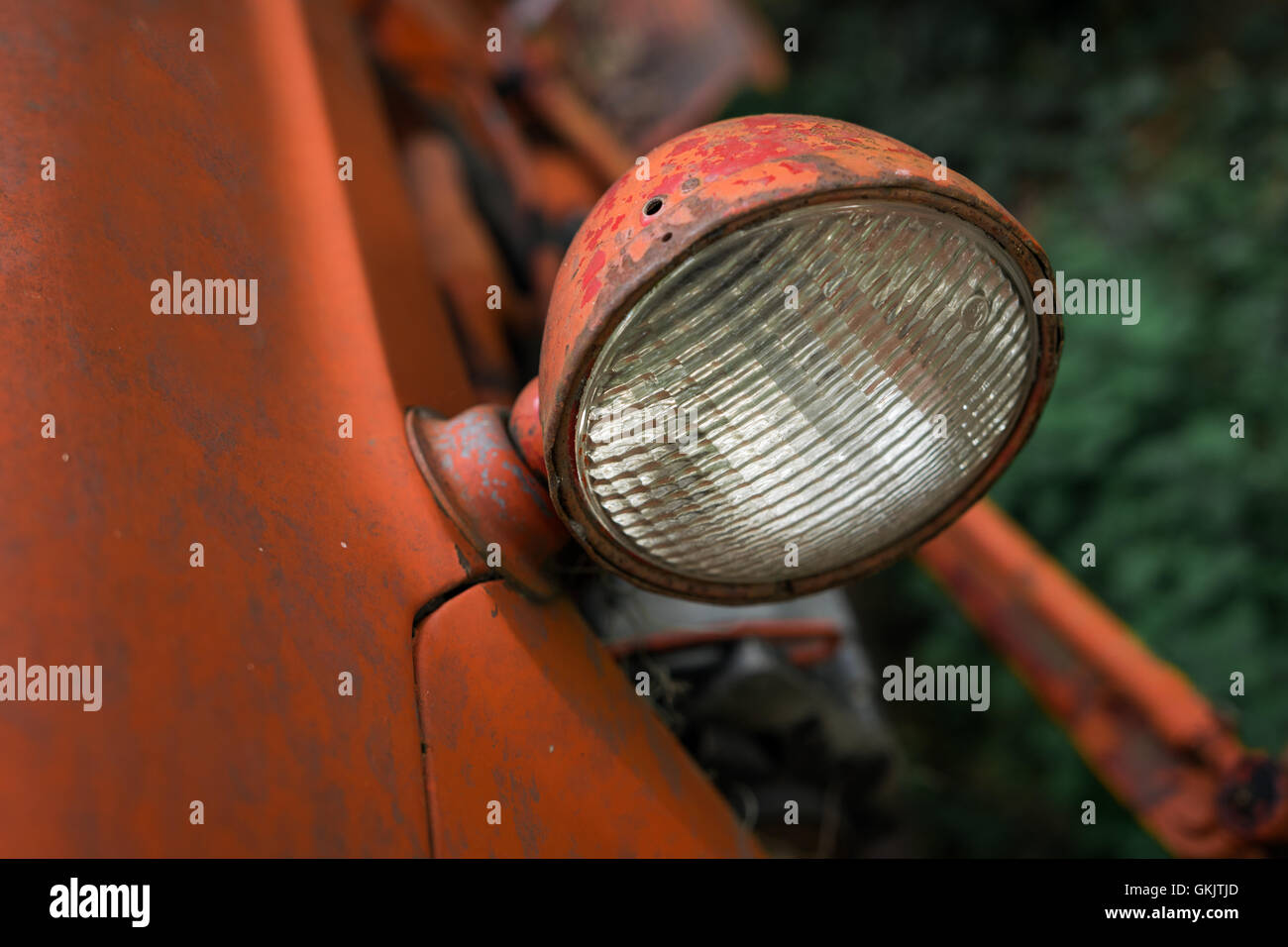 Un gros plan d'un projecteur d'un vieux tracteur rouillé dans une zone boisée. Banque D'Images