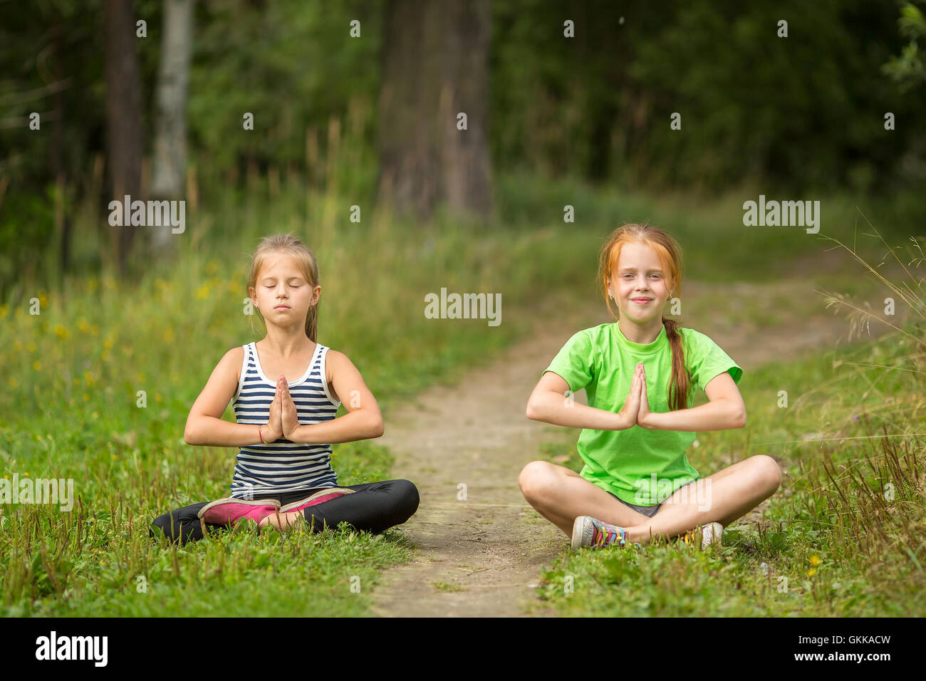 Deux petites filles assis en méditation de yoga en plein air. Banque D'Images