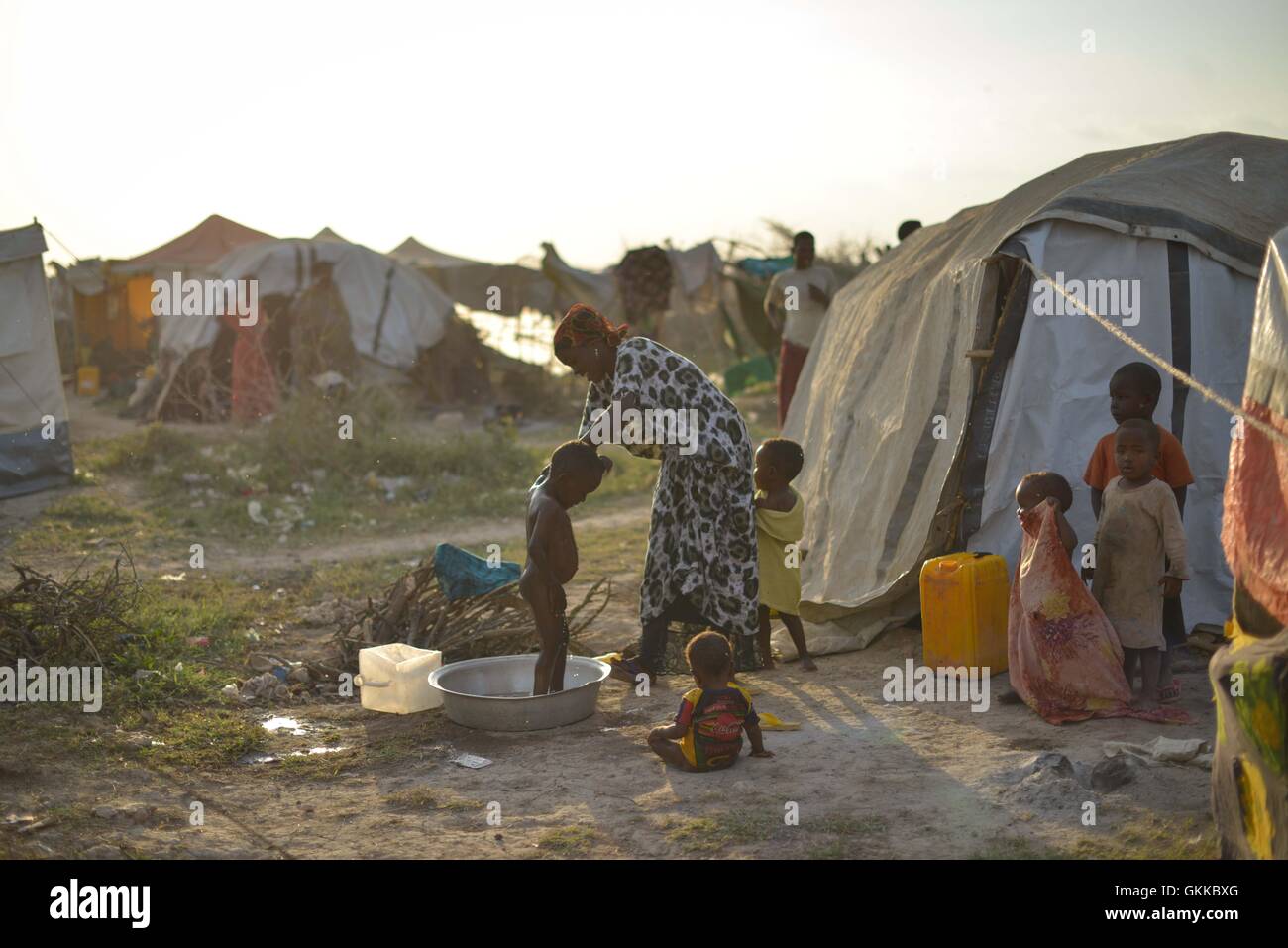 Le 14 décembre 2016, une mère a baigné son enfant à l'extérieur de leur refuge temporaire dans un camp de déplacés près de Jowhar, en Somalie. Plus de 12 000 personnes ont été déplacées en raison de combats claniques, et beaucoup ont cherché refuge près d'un camp militaire de l'Union africaine assurant la sécurité des personnes déplacées. Banque D'Images