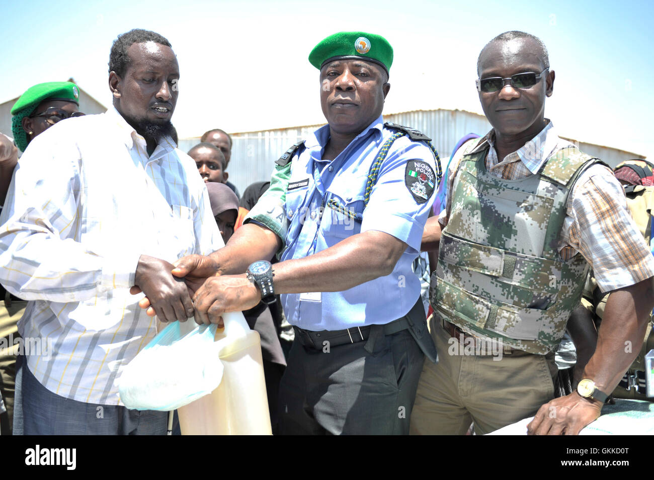 Bashir Mohamed, représentant des personnes aveugles dans le camp anciennement reçoit le don de denrées alimentaires provenant de l'AMISOM, Benoît, Eseigbe et officier de liaison humanitaire Senior, Abdul Diabagate, à un camp de personnes déplacées, Siliga Amerikanka, le 24 février 2014. Ce don composé de 10 sacs de riz, 3 sacs de maïs, 3 sacs de niébé, 3 sacs de sucre, de sel et de 20 gallons d'huile. Banque D'Images