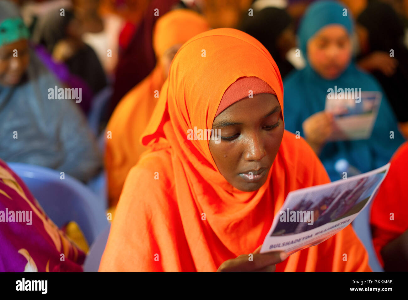 Le 6 août 2015, une jeune fille lit une affiche de police communautaire lors d’une Assemblée municipale dans le district de Shibis, à Mogadiscio. L'événement, organisé par la police de l'AMISOM, la force de police somalienne et les administrateurs locaux, était axé sur le renforcement de l'engagement communautaire et des efforts de maintien de l'ordre. Photo de Omar Abdisalan. Banque D'Images