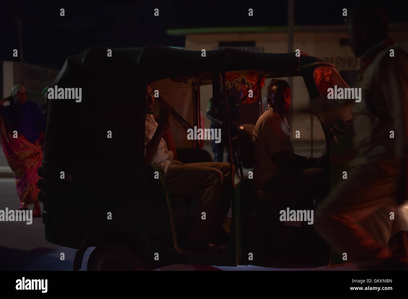 Un conducteur de tuktuk et son passager attendent d'être fouillés par des policiers somaliens à un poste de contrôle nocturne à Mogadiscio, en Somalie, le 23 octobre. Le poste de contrôle fait partie des mesures de sécurité en cours pour contrôler les mouvements et maintenir l'ordre dans la ville. Banque D'Images