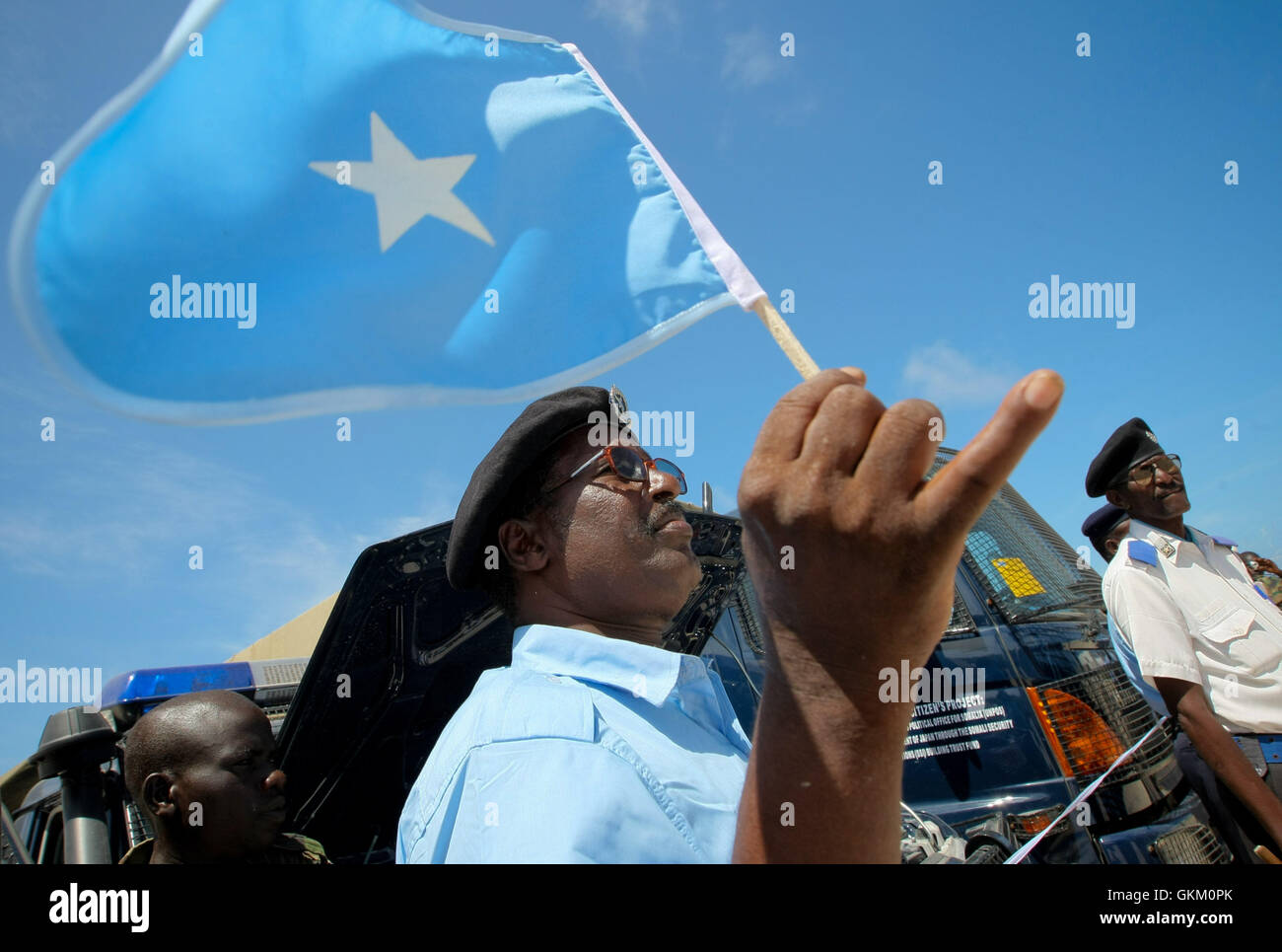 Le 7 mai, un officier de la police somalienne tient le drapeau national avant une cérémonie à Mogadiscio où le Japon, par l'intermédiaire de l'UNPOS, a fait don de matériel essentiel pour la reconstruction du FPS. Le don comprenait des véhicules, des casques et du matériel de communication pour améliorer les capacités opérationnelles de la force. Banque D'Images