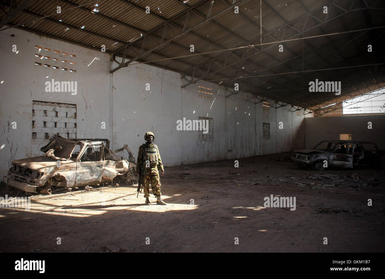 Le 2 octobre 2011, un soldat kenyan se tient devant des véhicules détruits par des frappes de missiles de l’armée de l’air kenyane à l’aéroport de Kismayo. Cette opération a ciblé les positions d'Al-Shabaab dans le cadre d'une offensive conjointe avec l'Armée nationale somalienne (SNA) et les forces pro-gouvernementales de la brigade de Ras Kimboni pour libérer la ville du contrôle extrémiste. AMISOM photo. Banque D'Images