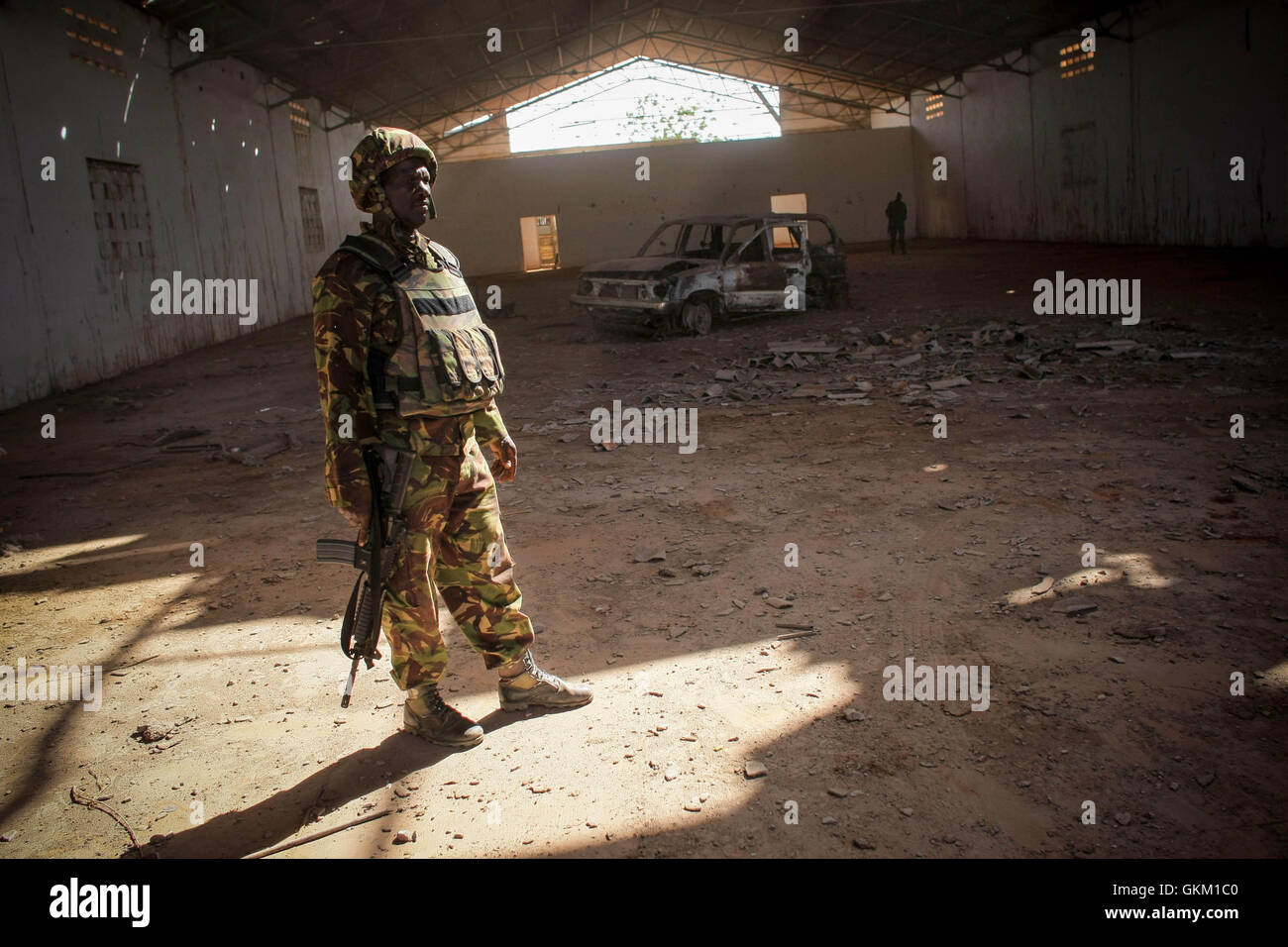 La SOMALIE, Kismayo : Dans un document de cours photographie prise le 02 octobre par l'Union africaine et l'équipe de soutien et d'information des Nations Unies publié le 03 octobre, un soldat du contingent kenyan de la Mission de l'Union africaine en Somalie (AMISOM) se place en avant d'un véhicule qui a été détruit une semaine plus tôt par l'Armée de l'Air Kenya frappes de missiles à l'intérieur d'un entrepôt à l'aéroport de Kismayo, formly sous le contrôle de l'Al-Qaeda-affilated groupe extrémiste Al Shabaab. Un joint-avance sur la ville portuaire de Kismayo en Somalie par les troupes de l'AMISOM kenyan, l'armée nationale somalienne (SNA et le gouvernement pro-Kimboni Ras mi-Brigade Banque D'Images