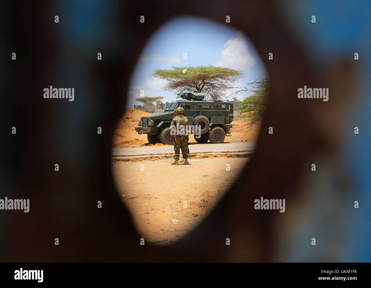 Le 5 octobre 2015, un soldat du contingent kenyan de l’AMISOM s’est tenu devant un véhicule blindé de transport de troupes, avec un trou de balle visible dans la porte de l’ancien complexe du HCR à Kismayo. Les forces de l'AMISOM procédaient à des balayages d'engins explosifs improvisés et sécurisaient la zone après qu'elle eut été libérée du contrôle d'Al-Chabab. / AU UN IST PHOTO Banque D'Images