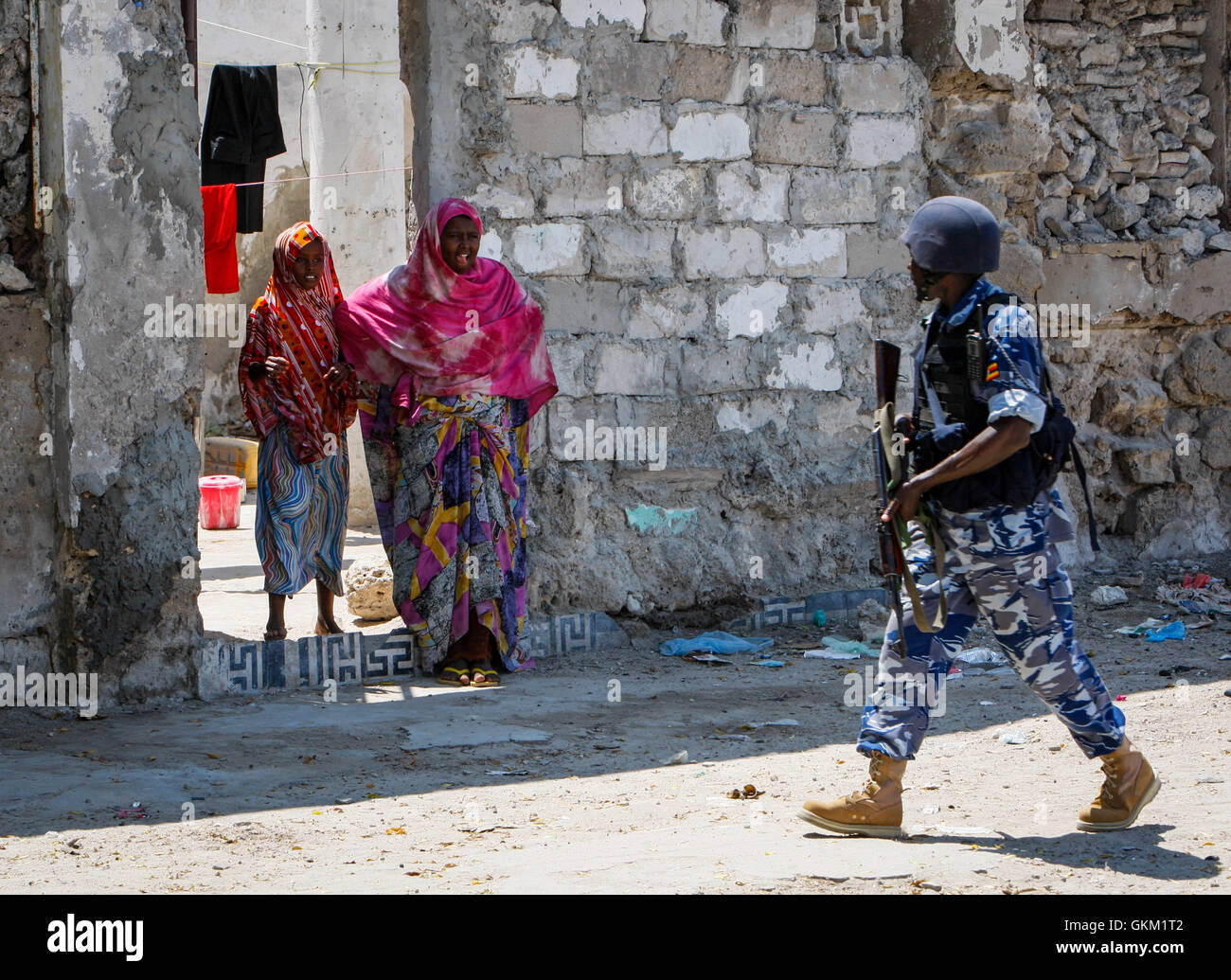 La Somalie, Mogadiscio : Dans un document de cours photos prises et publiées par l'Union africaine et l'équipe de support d'information des Nations Unies 09 novembre, une femme somalienne des gestes aussi un agent de la police ougandaise agissant comme partie d'une unité de police constituée (FPU) avec la Mission de l'Union de l'Union africaine en Somalie (AMISOM) marche dernières pendant une patrouille à pied dans le district de Kaa'ran dans la capitale Mogadishu. L'AMISOM FPUs travaillent avec leurs homologues de la Force de police somalienne (SPF) en contribuant à assurer la sécurité à Mogadiscio, en plus d'une formation et d'encadrement du SPF sur le maintien de l'ordre techniques et pratiques. IST UA-ONU PHO Banque D'Images