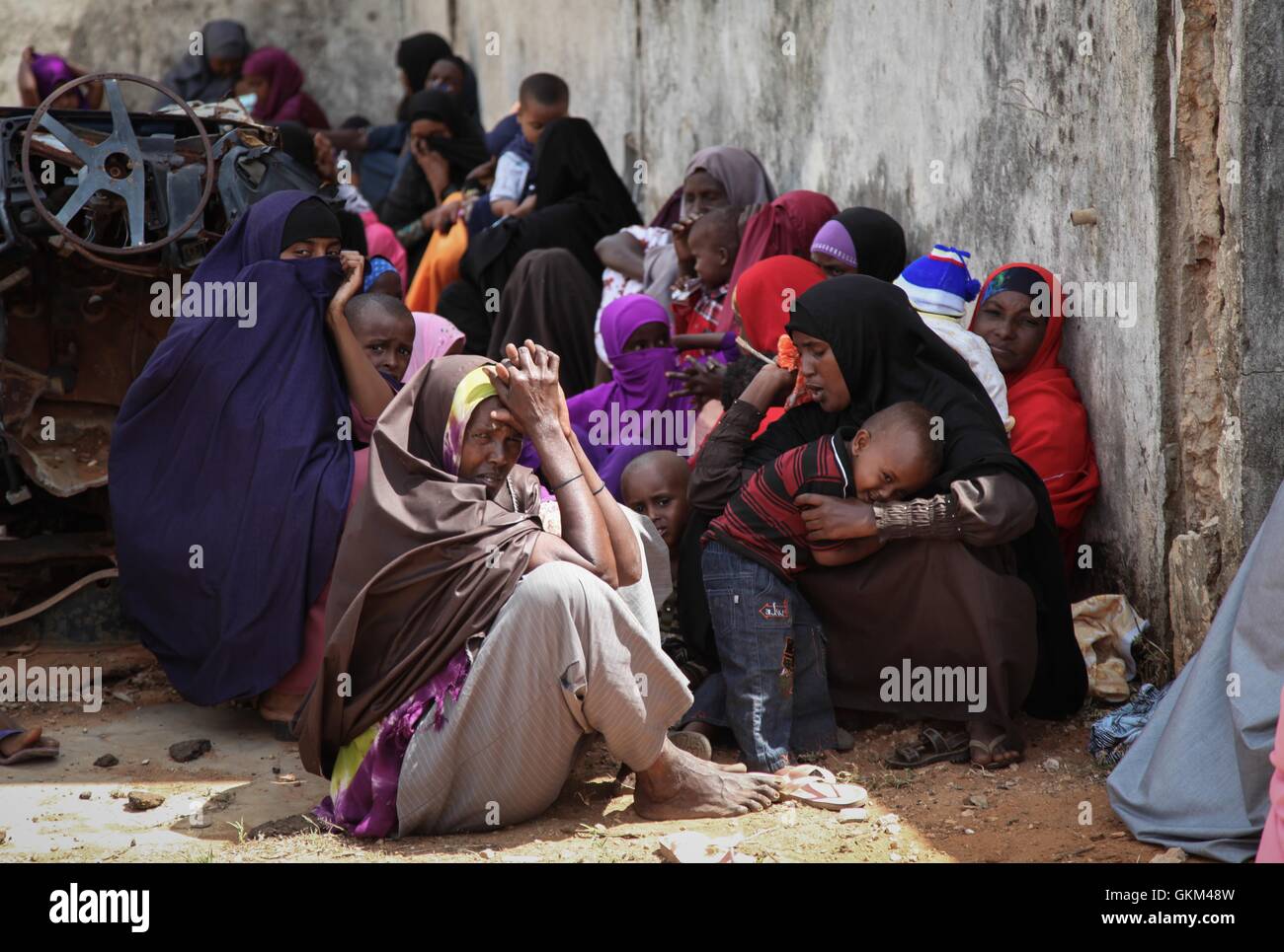 La SOMALIE, Kismayo : Dans un photogragh prises le 19 août 2013 et publié par l'Union africaine et l'équipe de support d'information des Nations Unies 31 août, les femmes et les enfants d'attendre dans l'ombre d'un bâtiment abandonné pour voir un médecin dans une clinique médicale gratuite fournie par le contingent Kenyan avec la Mission de l'Union africaine en Somalie (AMISOM) dans le sud de la ville portuaire de Kismayo en Somalie. Ouvert 7 jours par semaine et de voir une moyenne de 80 patients par jour à partir de Kismayo et ses villages, le personnel médical de l'AMISOM fournir les soins de santé gratuits pour les civils de Kismayo, traiter une variété de cas y compris le paludisme, Banque D'Images