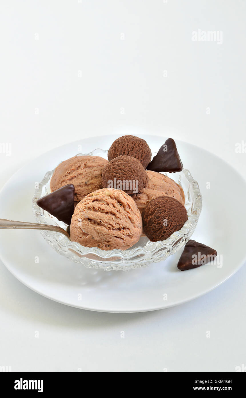 Boules de glace au chocolat et glace noisette dans un bol blanc, gros plan, macro, fond blanc, vertical Banque D'Images