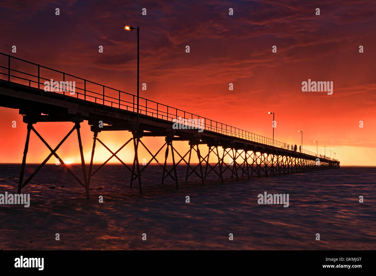 Hellish rouge coucher de soleil sur l'horizon de la mer derrière la jetée en bois historique de Ceduna ville sur Grande Baie australienne. Le temps orageux rend Banque D'Images
