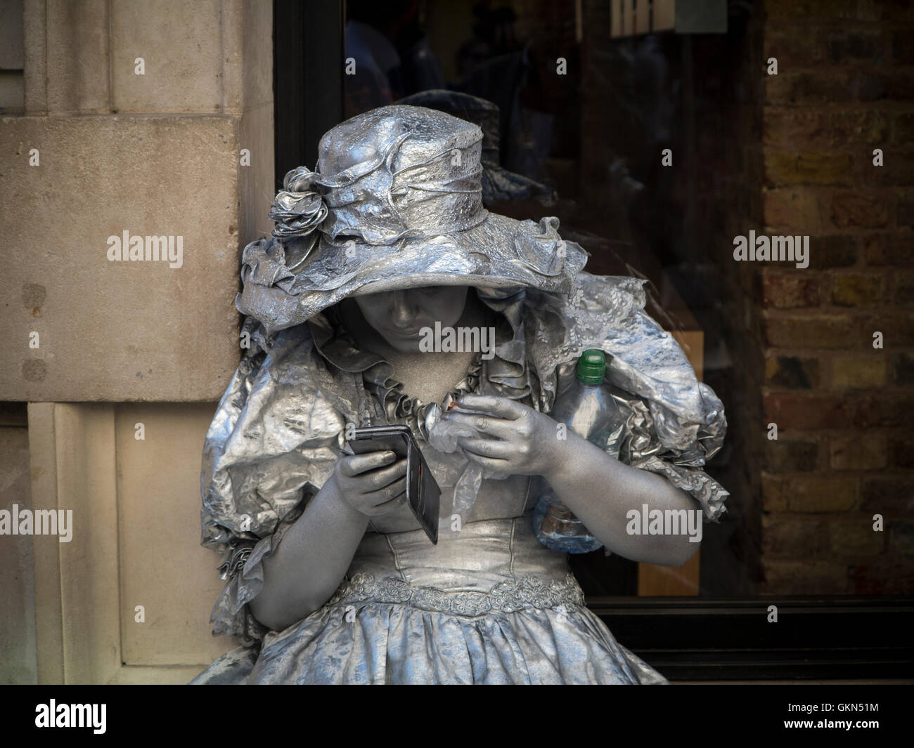 Une statue vivante ayant une pause et consultation des messages sur son smartphone Banque D'Images
