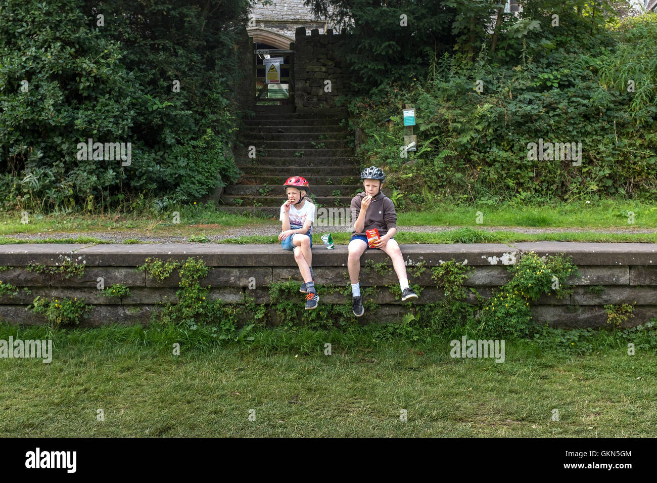 Deux enfants sont assis sur la plate-forme d'une gare désaffectée sur le sentier Monsal dans le Peak District, Derbyshire Banque D'Images