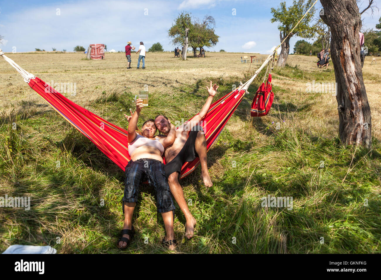 Les gens apprécient un couple de jour dans un hamac de jardin buvant de la bière République tchèque chaud d'été se détendre bien être bonne humeur Banque D'Images