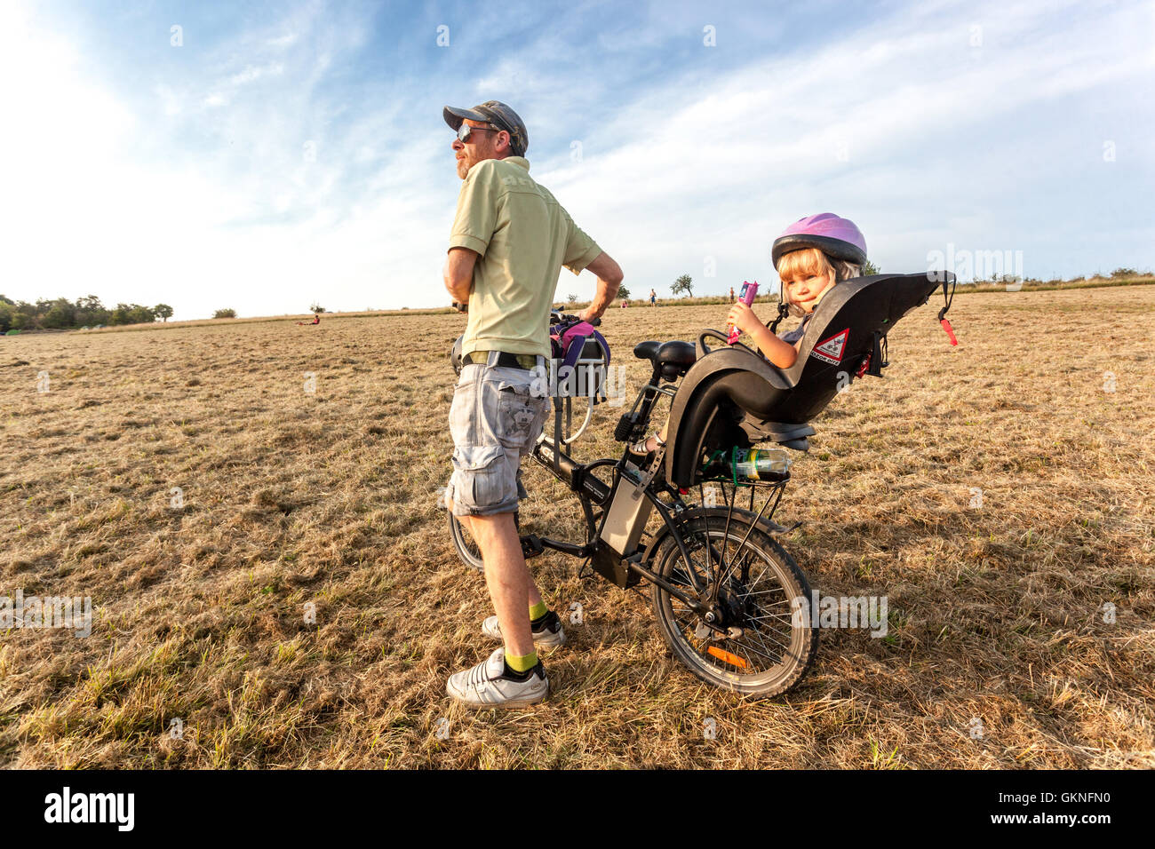 Père et sa fille bien-aimée dans une prairie d'été sur un vélo dans un siège pour enfant, République Tchèque Banque D'Images