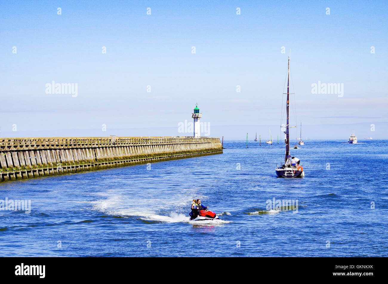 Yachts et un scooter sur la rivière de la Touques à Deauville, en France, à la jetée et phare de Deauville dans l'arrière-plan Banque D'Images