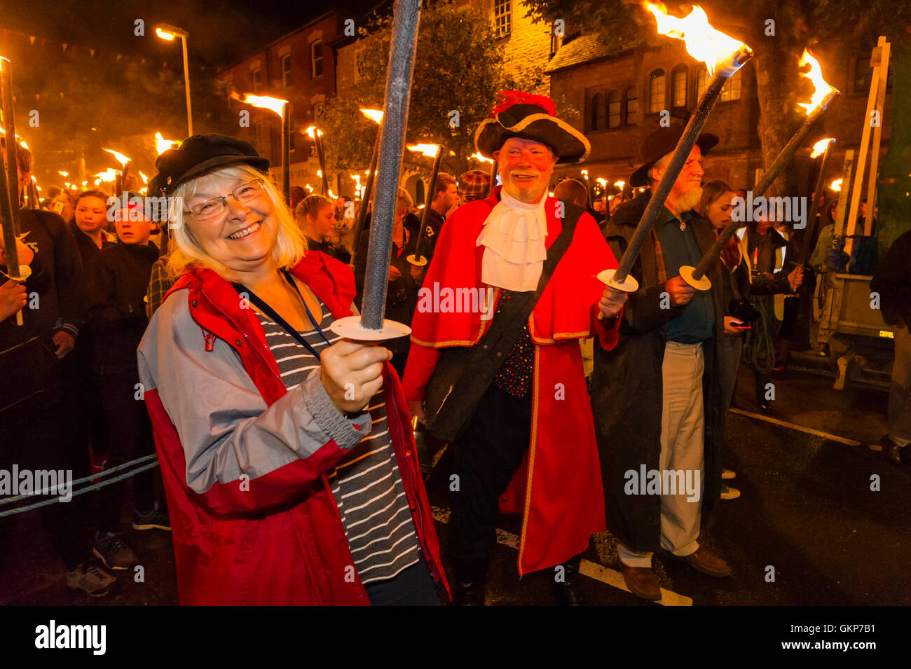 Bridport, Dorset, UK. Août 21, 2016. Adjoint au maire Anne Rickard, crieur public John Collingwood et David Rickard avec leurs torches allumées le long avec environ 2 000 autres personnes qui ont pris part à l'Assemblée Bridport Carnival défilé aux flambeaux qui part de Bridport Town Hall et va à un mille et demi à West Bay Beach. Crédit photo : Graham Hunt/Alamy Live News Banque D'Images