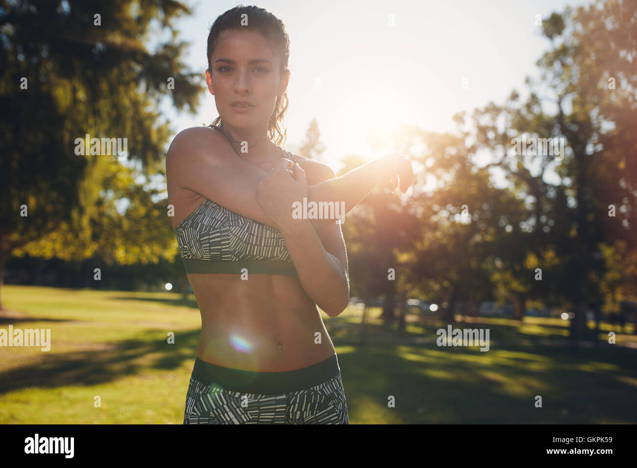 Jeune femme étirant les bras avant une course à l'extérieur. femme de fitness faisant de l'exercice d'échauffement au parc sur une journée ensoleillée. Banque D'Images